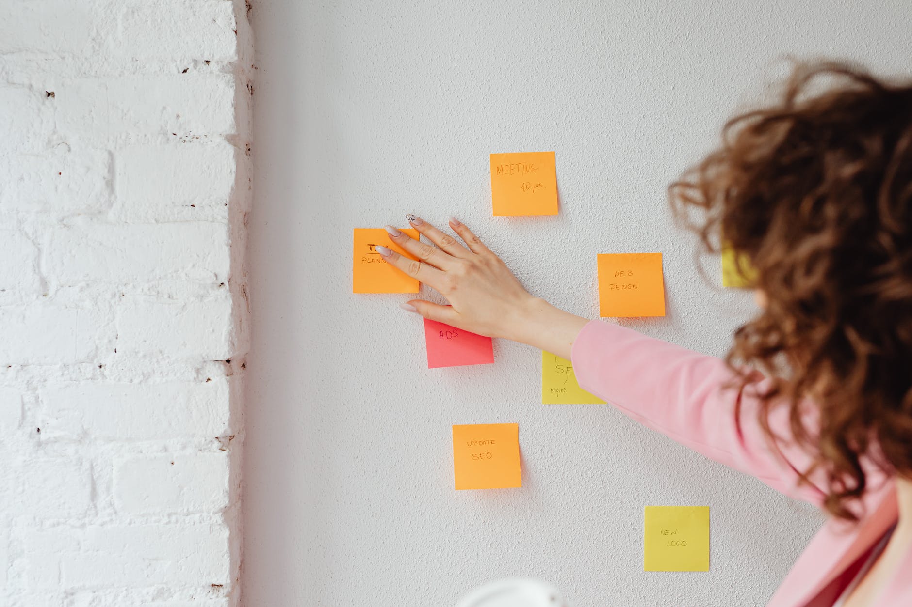 woman in pink long sleeve shirt sticking post its on the wall