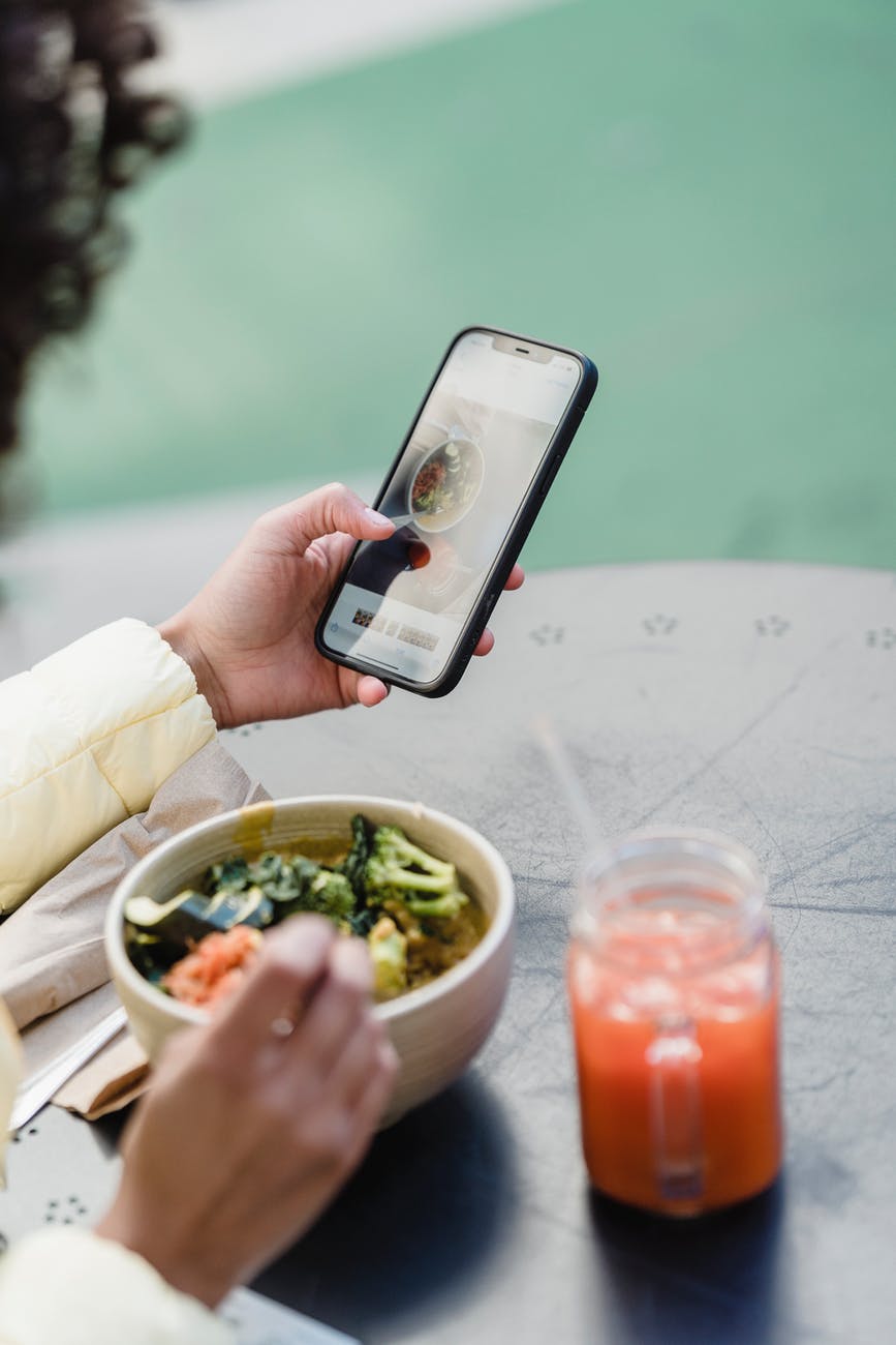 social media influencer with smartphone and tasty vegetarian salad in cafeteria